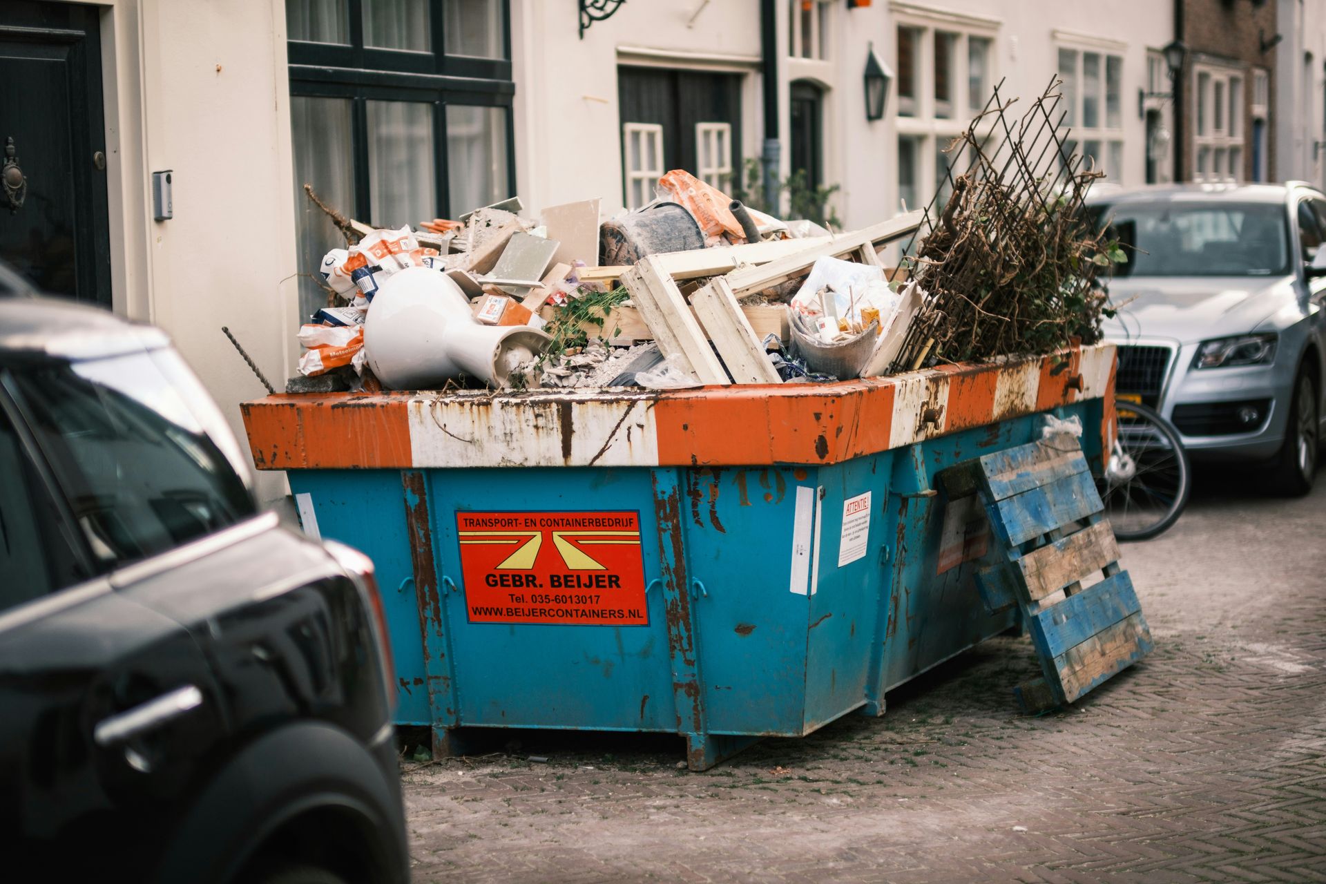 a blue dumpster filled with lots of trash on the side of a road